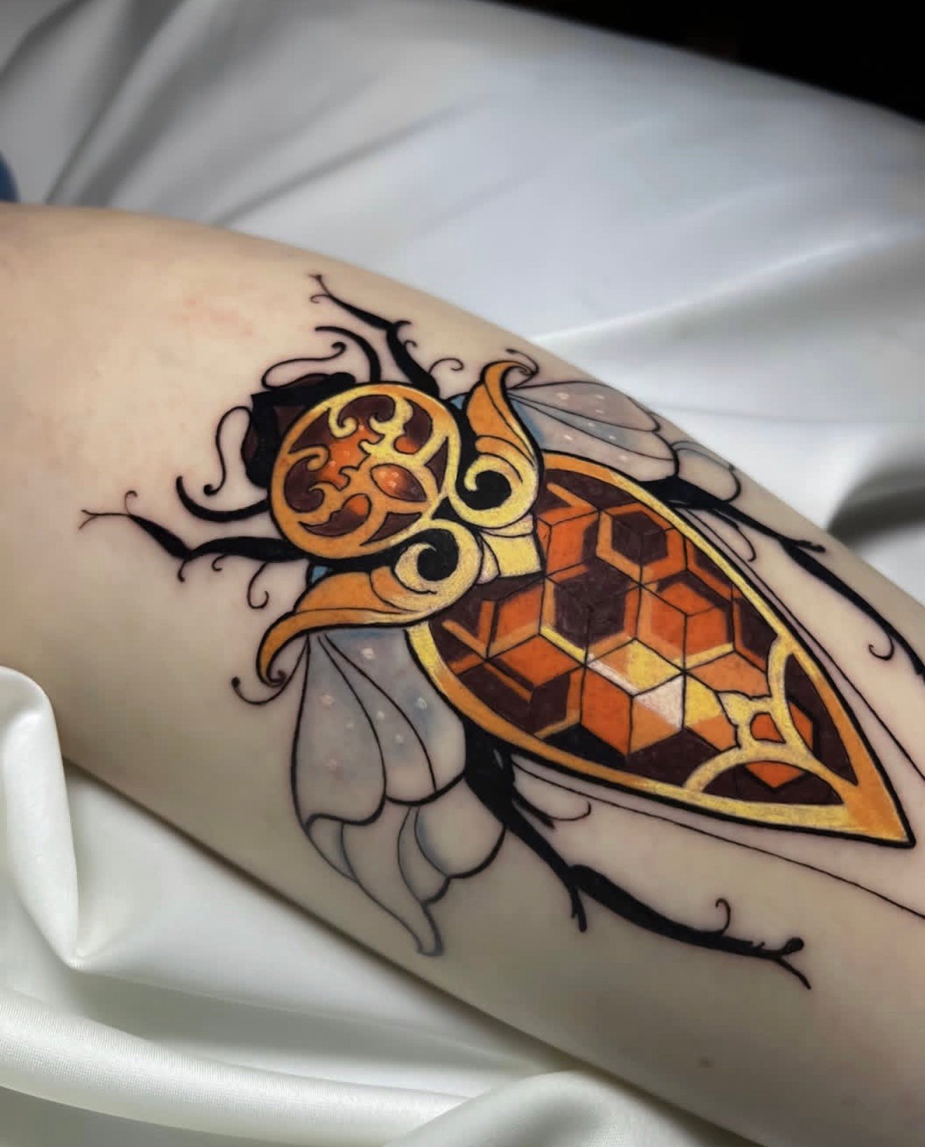 illustrative color tattoo of an ornamental insect with geometric patterns, warm tones and fine line details